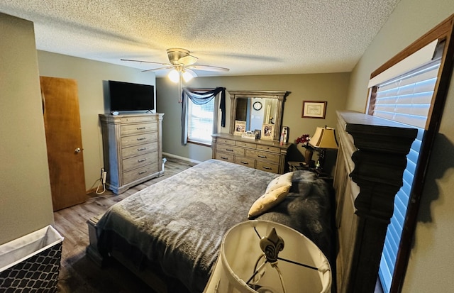 bedroom featuring light wood finished floors, a textured ceiling, baseboards, and a ceiling fan