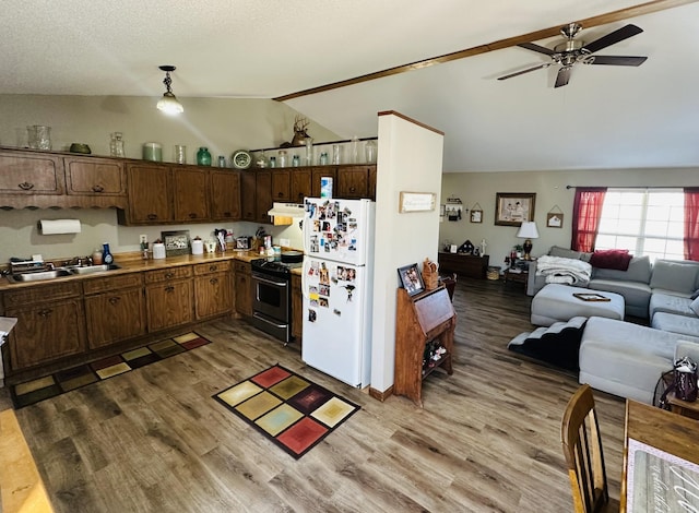 kitchen with range with gas cooktop, freestanding refrigerator, open floor plan, vaulted ceiling, and a sink