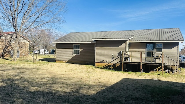 rear view of house with metal roof, a yard, and a wooden deck