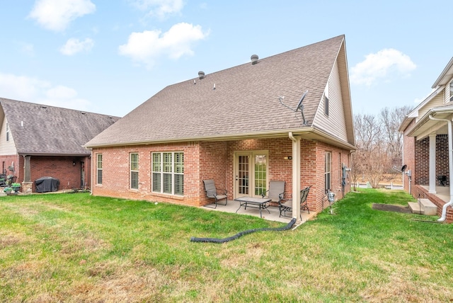 back of property featuring a patio area, a shingled roof, a lawn, and brick siding