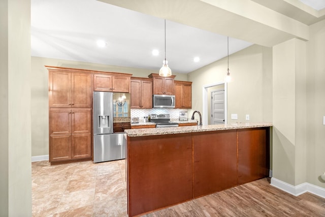 kitchen with brown cabinets, backsplash, appliances with stainless steel finishes, light stone countertops, and a peninsula