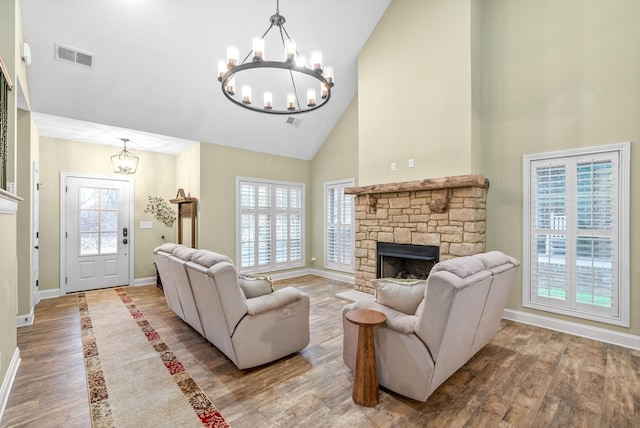 living room featuring baseboards, a fireplace, visible vents, and wood finished floors