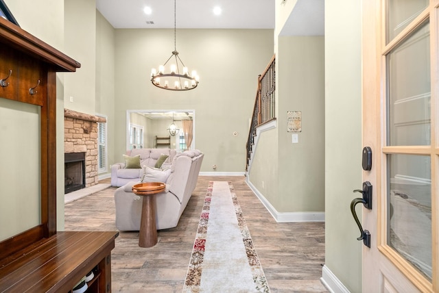 living area featuring baseboards, stairway, wood finished floors, a fireplace, and a chandelier