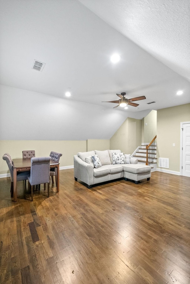 living area with lofted ceiling, visible vents, and wood finished floors