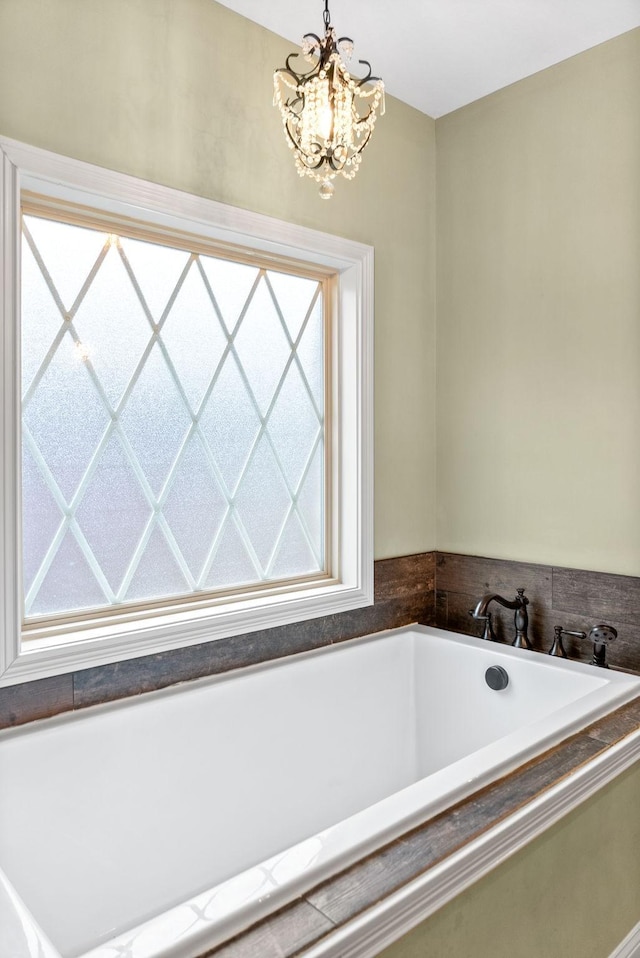 full bath featuring a chandelier and a bath