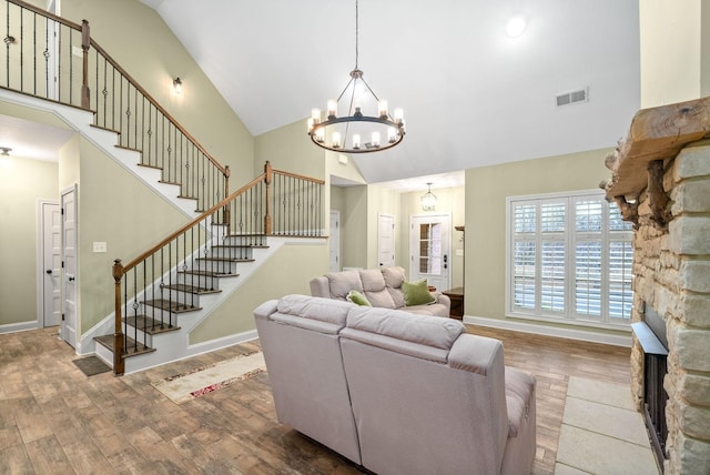 living room featuring visible vents, wood finished floors, high vaulted ceiling, baseboards, and stairs