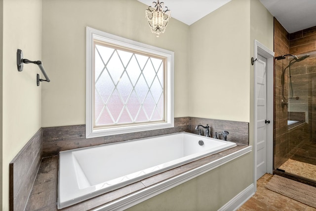 bathroom with a stall shower, a bath, and a notable chandelier