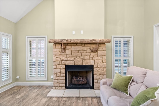 living area with high vaulted ceiling, a fireplace, baseboards, and wood finished floors