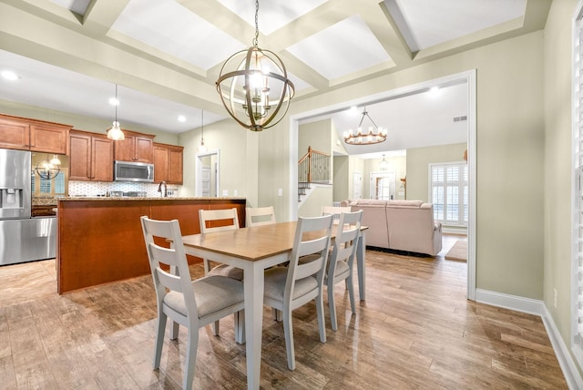 dining space featuring baseboards, coffered ceiling, light wood-style flooring, and an inviting chandelier