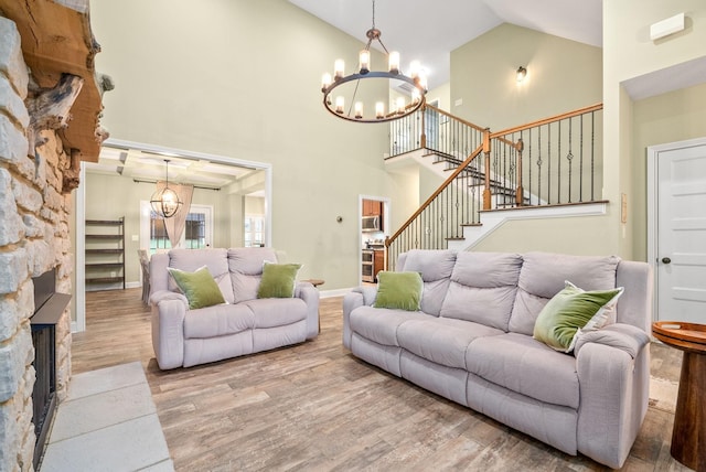 living room featuring an inviting chandelier, stairway, high vaulted ceiling, and wood finished floors