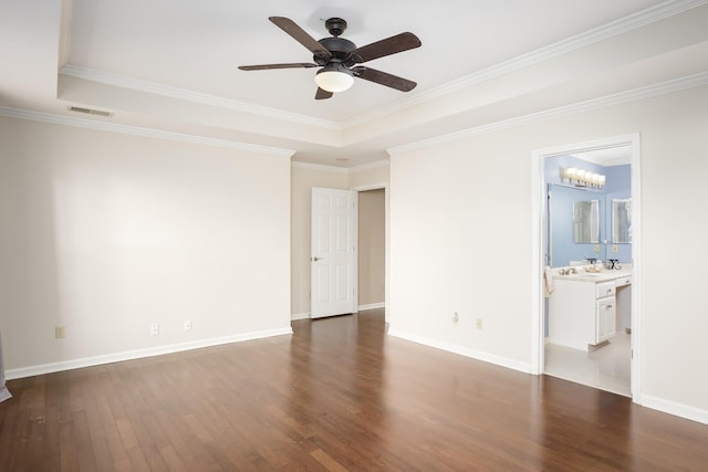 spare room with a ceiling fan, baseboards, a tray ceiling, and dark wood-type flooring