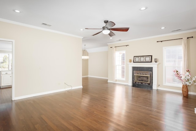 unfurnished living room with crown molding, a tile fireplace, plenty of natural light, and wood finished floors