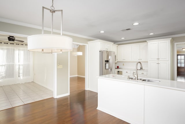 kitchen featuring dark wood-style flooring, a sink, visible vents, ornamental molding, and stainless steel fridge with ice dispenser