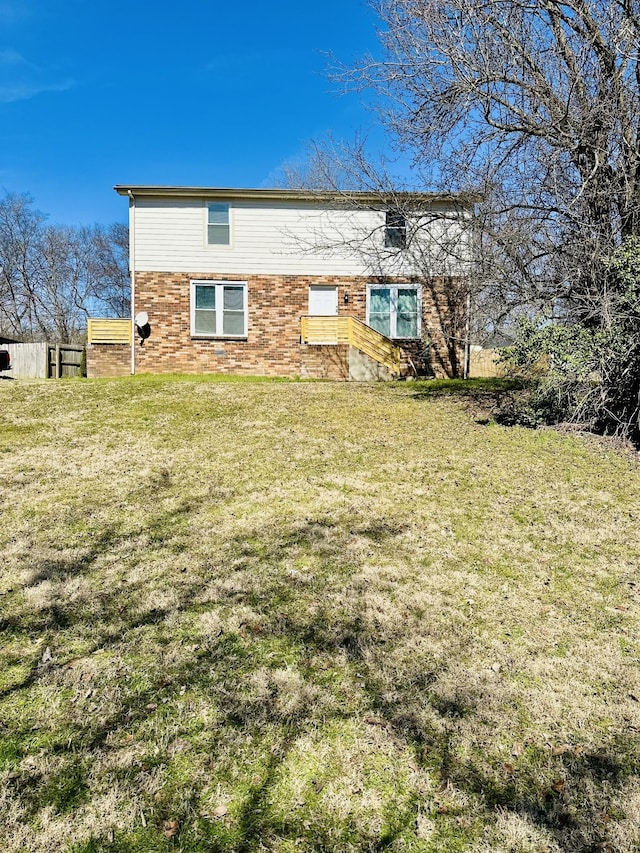 rear view of property with brick siding and a lawn