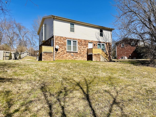 back of house featuring brick siding and a lawn