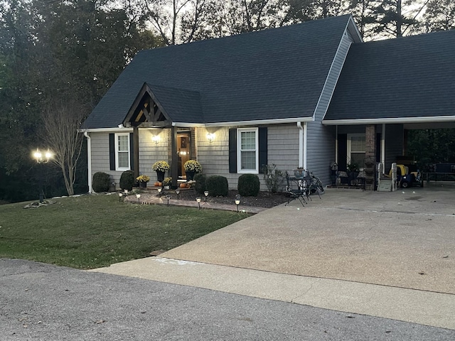 cape cod home featuring concrete driveway, roof with shingles, and a front lawn