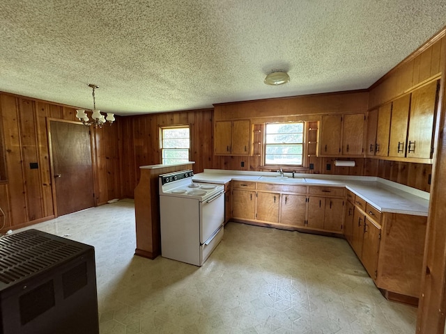 kitchen featuring a peninsula, light countertops, white range with electric stovetop, brown cabinets, and light floors