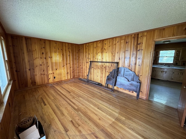 empty room with a textured ceiling, baseboards, wood finished floors, and wooden walls