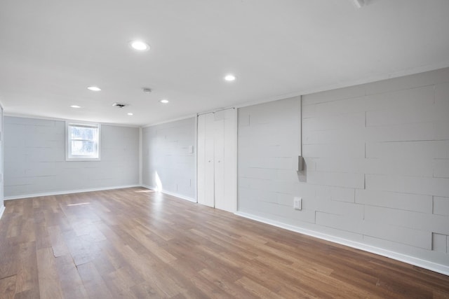 spare room featuring recessed lighting, wood finished floors, visible vents, baseboards, and concrete block wall