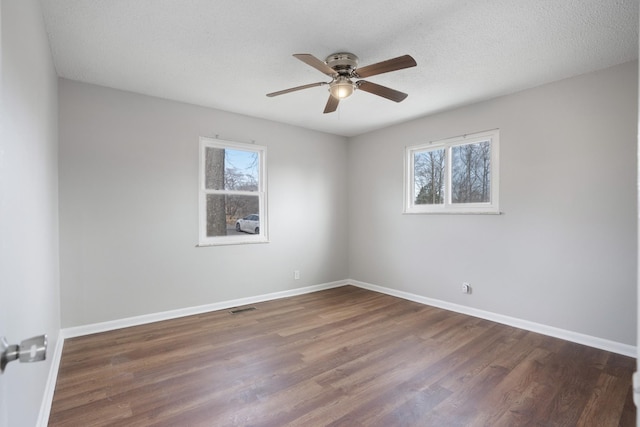 spare room featuring a textured ceiling, wood finished floors, visible vents, and baseboards