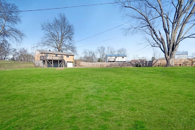 view of yard featuring a deck, stairway, and fence