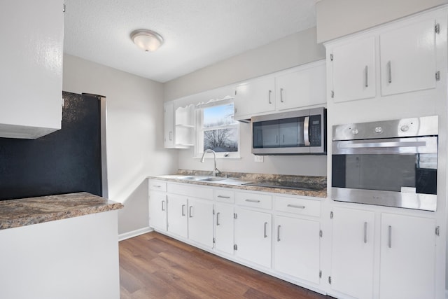 kitchen featuring stainless steel appliances, white cabinets, dark wood-type flooring, and a sink