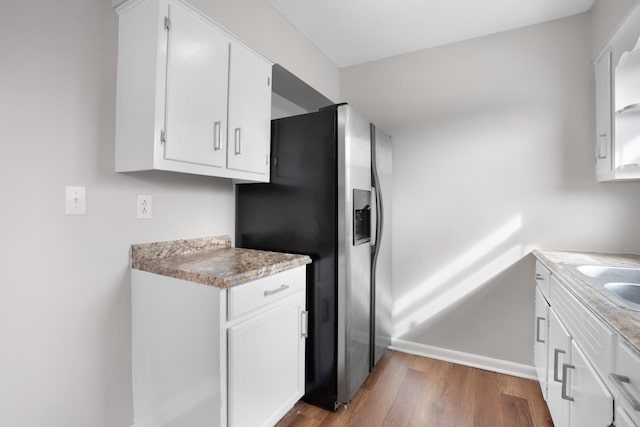 kitchen with light countertops, dark wood-style flooring, white cabinetry, and stainless steel fridge with ice dispenser