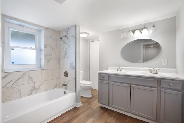 full bathroom with toilet, double vanity, a sink, and wood finished floors