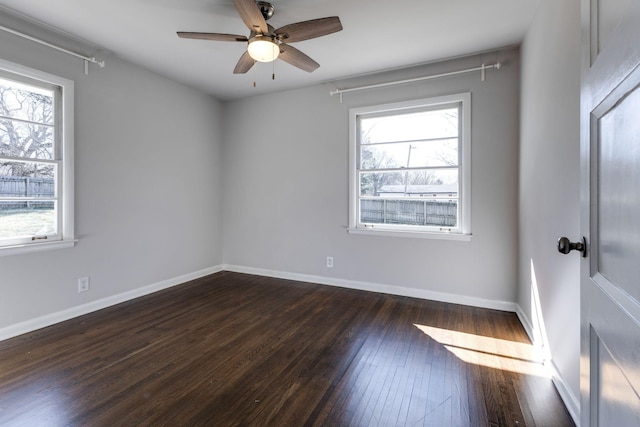 empty room with dark wood-style floors, plenty of natural light, a ceiling fan, and baseboards