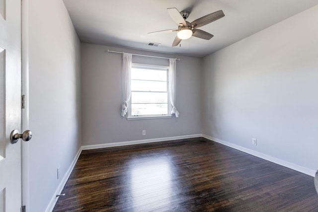 unfurnished room with dark wood-style floors, baseboards, visible vents, and a ceiling fan