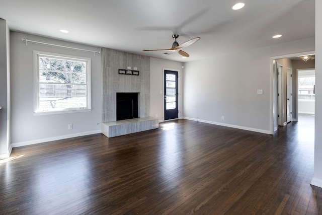 unfurnished living room featuring dark wood-style floors, recessed lighting, a large fireplace, and baseboards