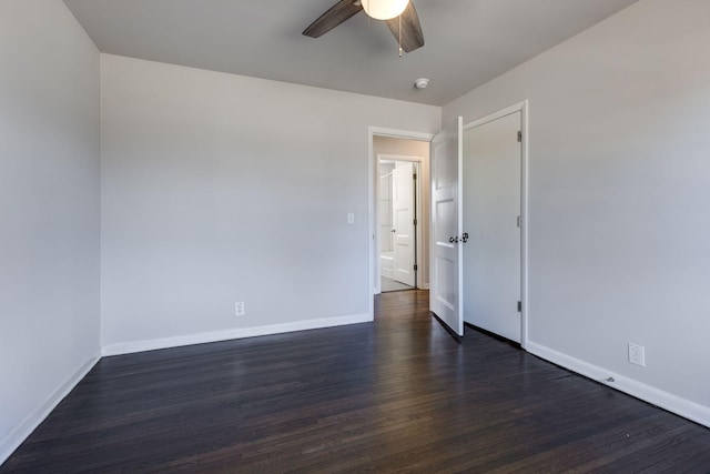 spare room featuring dark wood-type flooring, ceiling fan, and baseboards