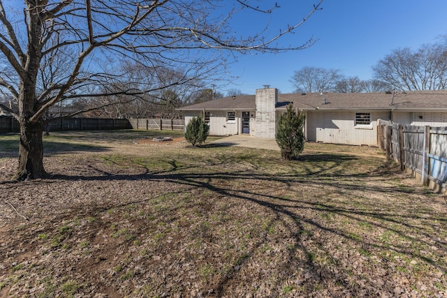 back of property featuring brick siding, a patio, a chimney, a lawn, and a fenced backyard