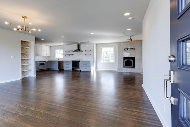 living room featuring a wealth of natural light, a large fireplace, and dark wood-style flooring