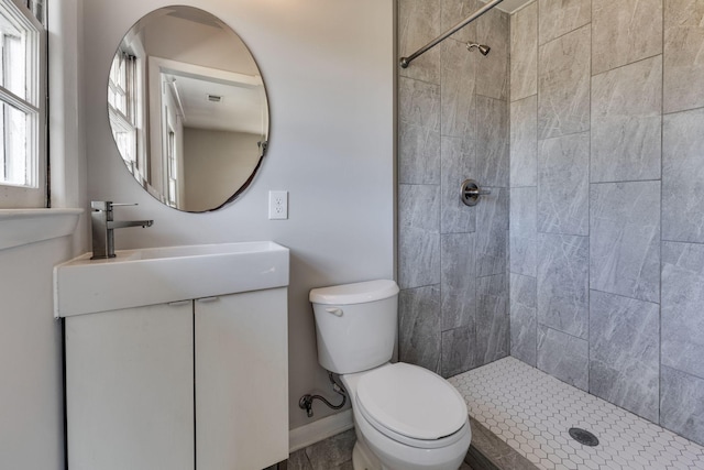 full bath with baseboards, a tile shower, vanity, and toilet