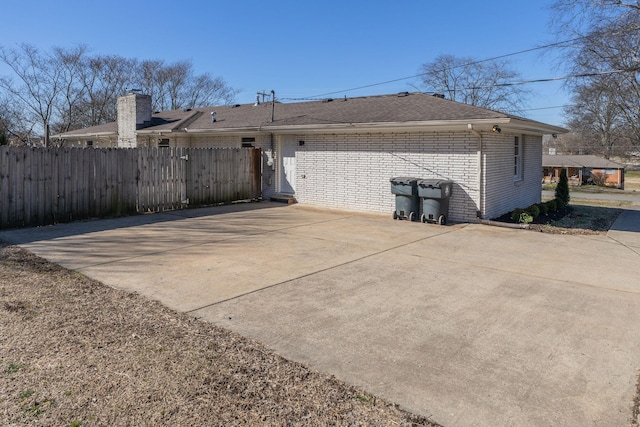 view of property exterior with brick siding and fence