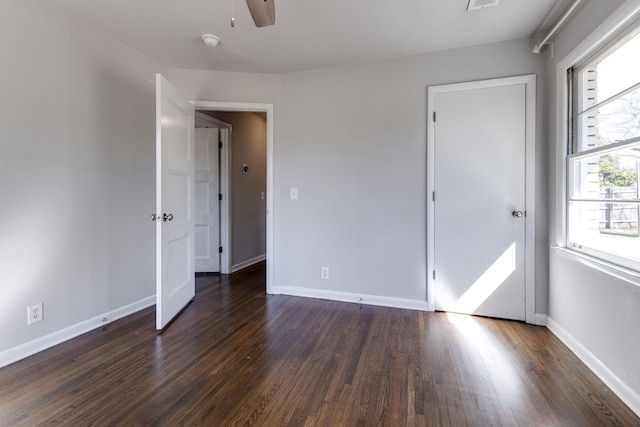 unfurnished bedroom with dark wood finished floors, a ceiling fan, and baseboards