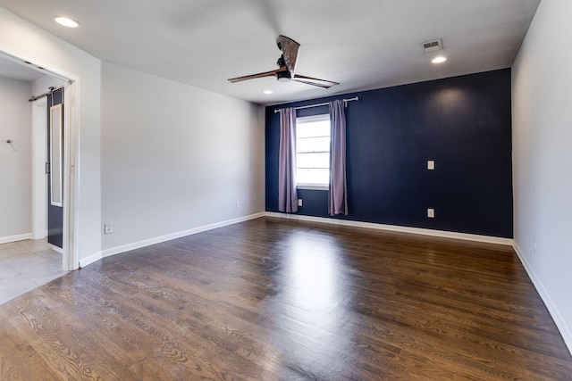 empty room featuring ceiling fan, visible vents, and baseboards