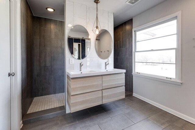 bathroom featuring double vanity, baseboards, walk in shower, and a sink