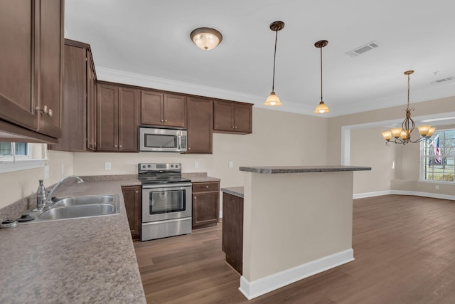 kitchen with wood finished floors, a sink, visible vents, ornamental molding, and appliances with stainless steel finishes