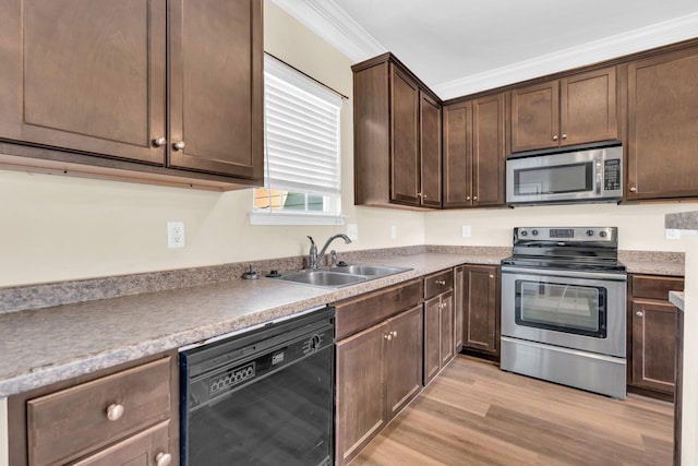 kitchen with appliances with stainless steel finishes, ornamental molding, dark brown cabinets, light wood-style floors, and a sink