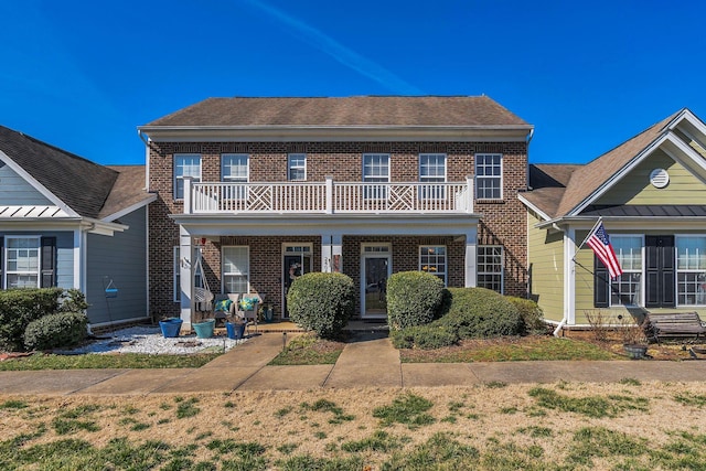 view of front of home with a balcony, covered porch, and brick siding