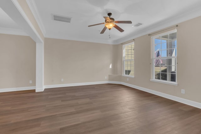 spare room with dark wood-style floors, baseboards, visible vents, and crown molding