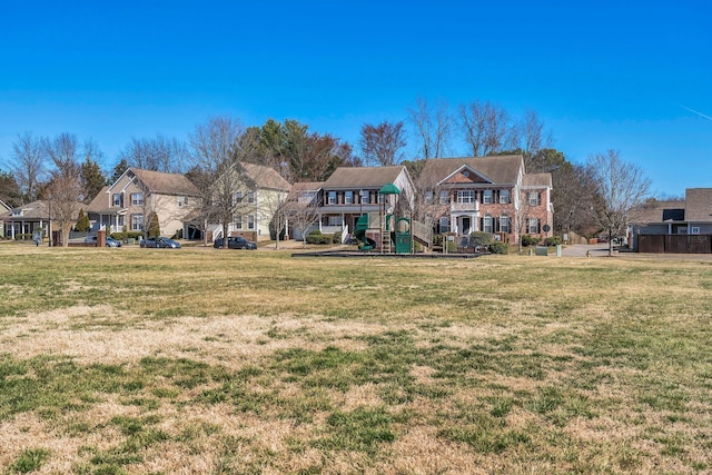 view of front of home featuring playground community, a front yard, and a residential view