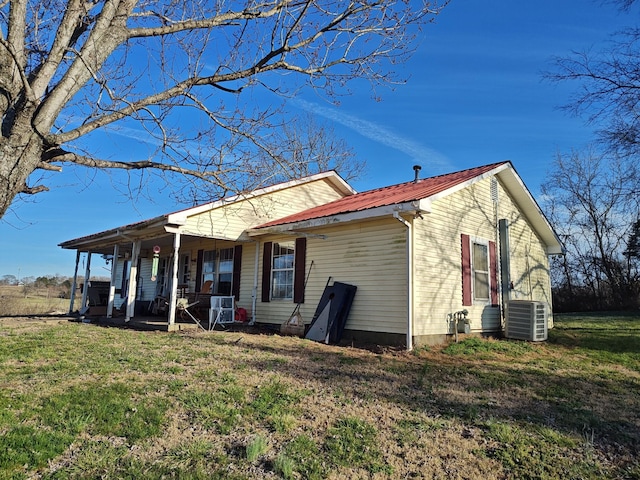 exterior space featuring covered porch, a yard, central AC unit, and metal roof