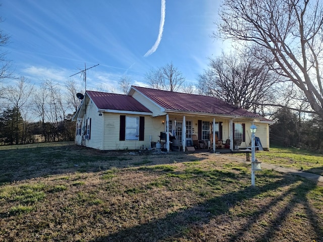 view of front facade featuring a porch, metal roof, and a front lawn