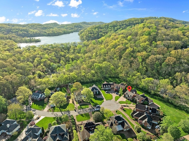 drone / aerial view featuring a water view, a residential view, and a wooded view