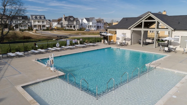 community pool featuring a patio area, fence, and a residential view