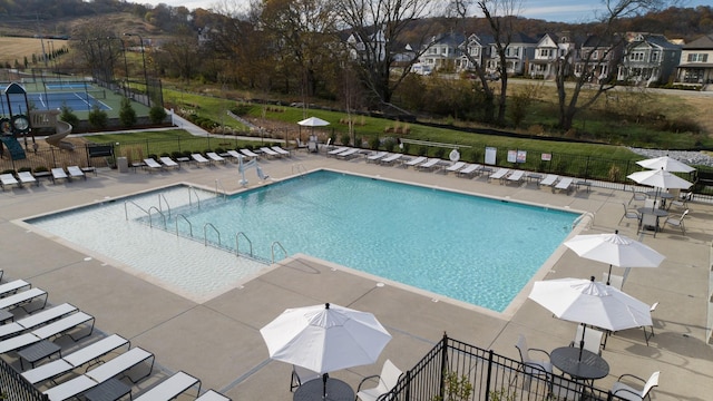 community pool featuring a residential view, a patio area, and fence