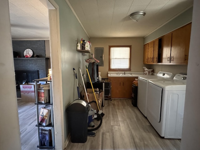 washroom featuring cabinet space, light wood-style floors, ornamental molding, a brick fireplace, and independent washer and dryer